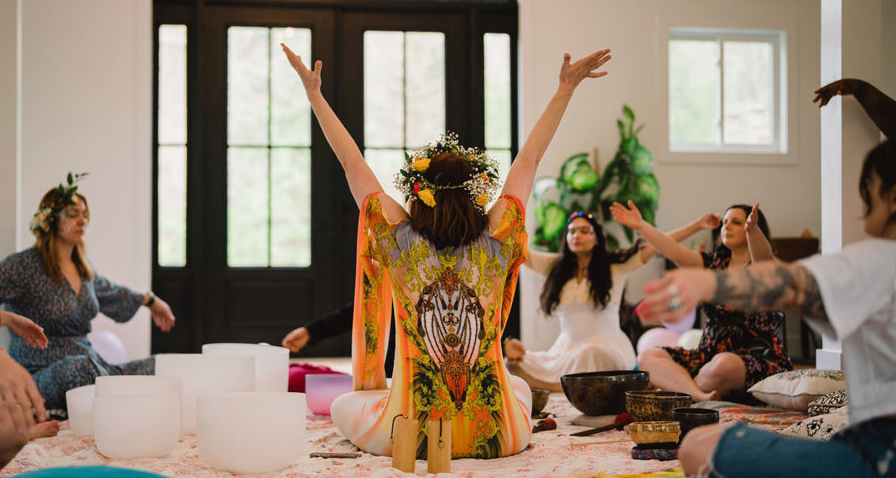 A group sound session, arms raised, surrounded by crystal bowls