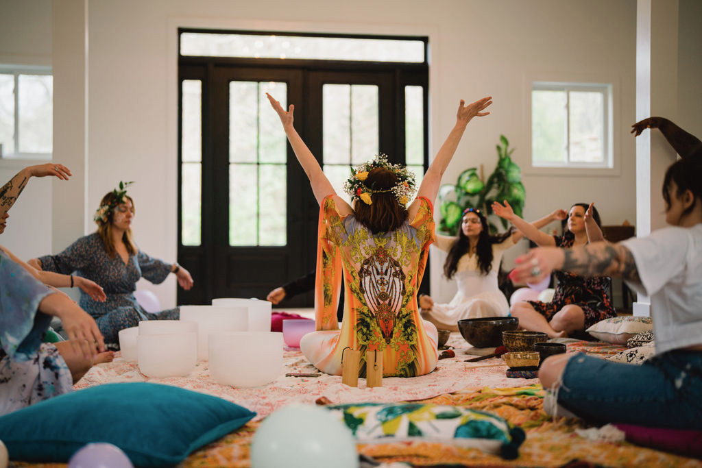 A group session with arms raised, surrounded by crystal bowls